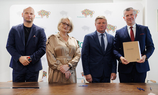 Wicemraszałek wiesława Burnos Wicemarszałek Marek Malinowski i Burmistrza Łap Krzystzof Gołaszewski stoja uśmiechnięci z podpisaną umową