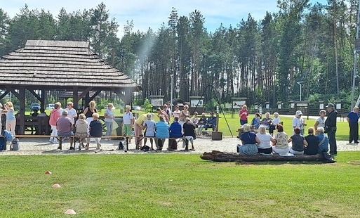 seniorzy piknikują przed wieżą widokową w Uhowie pod wiatami