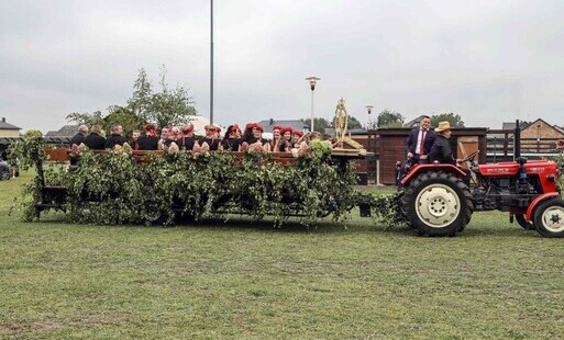 Traktor ciagnie wóz, na którym jadą mieszkańcy wsi Roszki-Wodźki w ludowych strojach